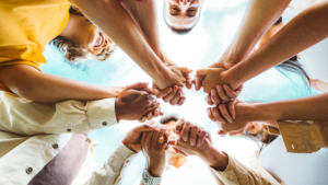 Hands of diverse people joined together in a circle, symbolizing unity, support, and community healing.
